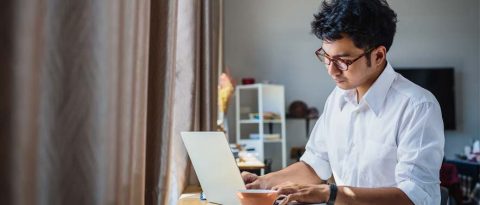 Joven investigando automóviles en su computadora portátil