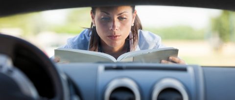 Una mujer leyendo manual en capó del automóvil nuevo