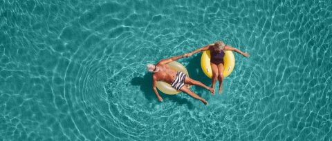 Desde arriba, pareja madura y relajada flotando en el mar.